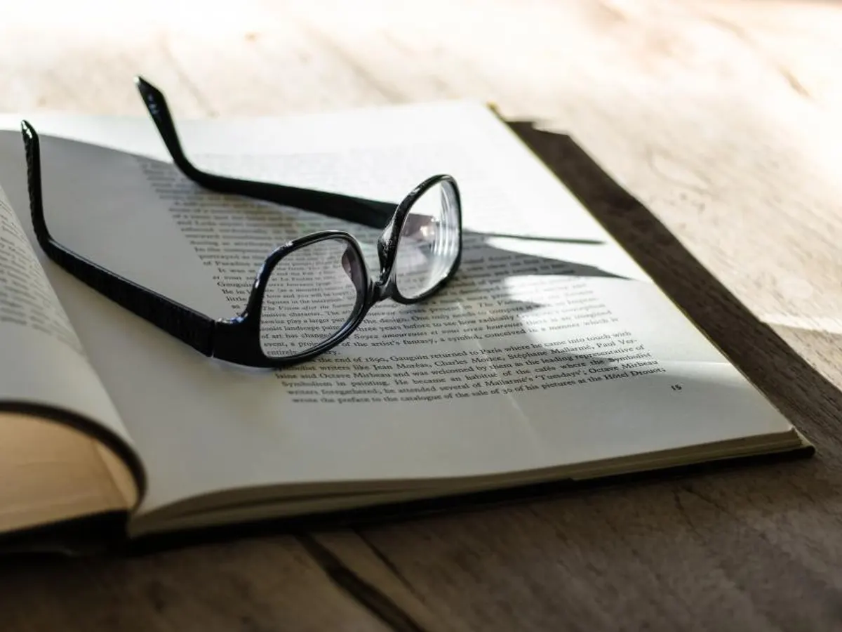 Kacamata di atas buku terbuka yang tersinari matahari