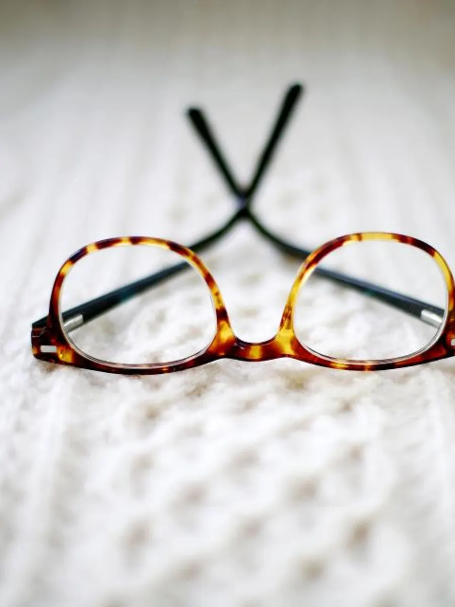 Kacamata bulat bermotif tortoise di atas rajutan putih